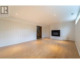 A spacious room with wooden flooring and a fireplace.