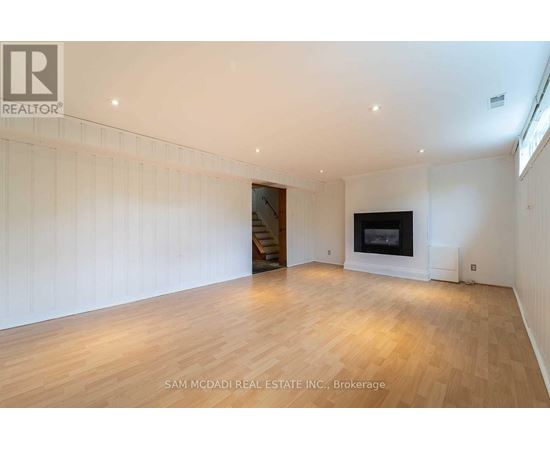 A spacious room with wooden flooring and a fireplace.