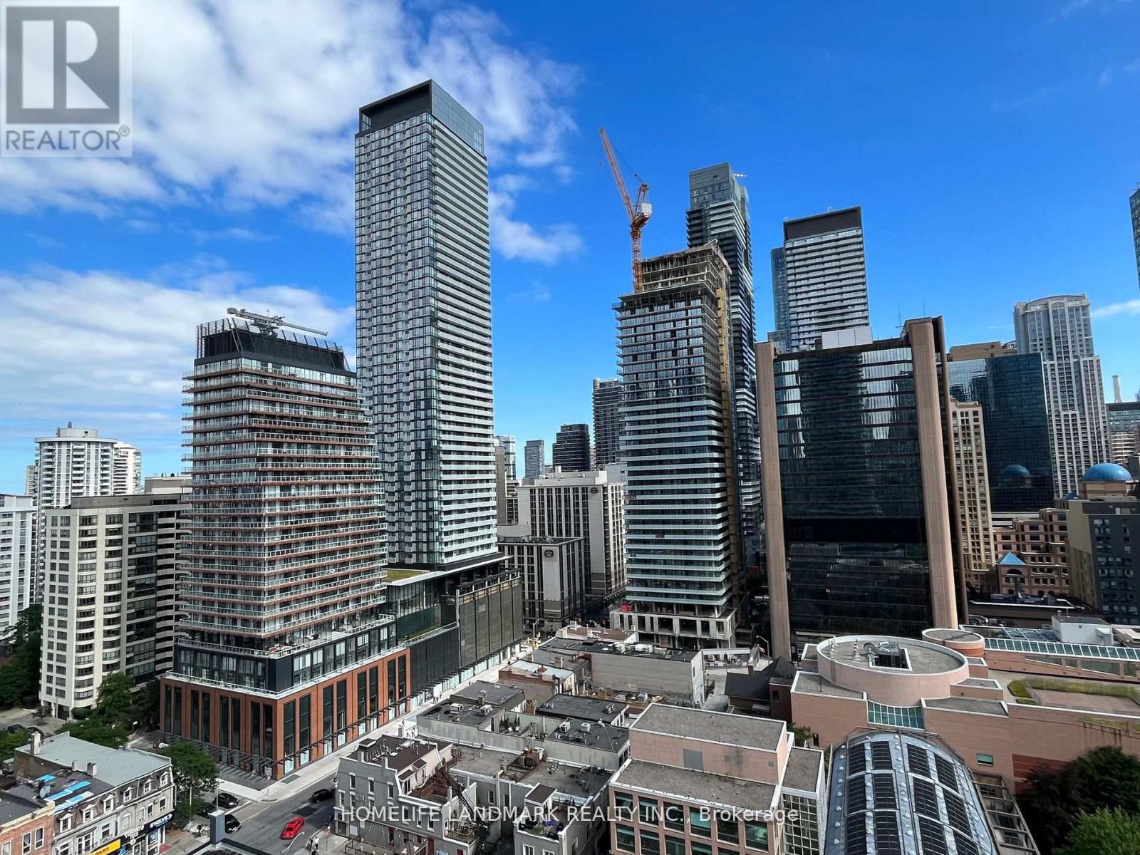 A cityscape with a clear blue sky and a crane visible in the distance.