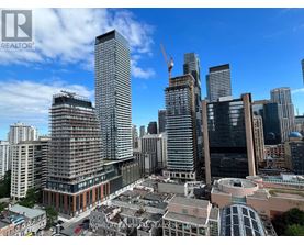 A cityscape with a clear blue sky and a crane visible in the distance.
