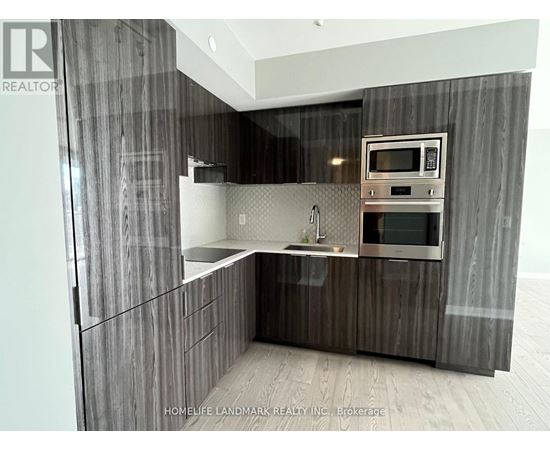 A modern kitchen with dark wood cabinets and stainless steel appliances.