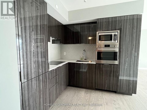 A modern kitchen with dark wood cabinets and stainless steel appliances.