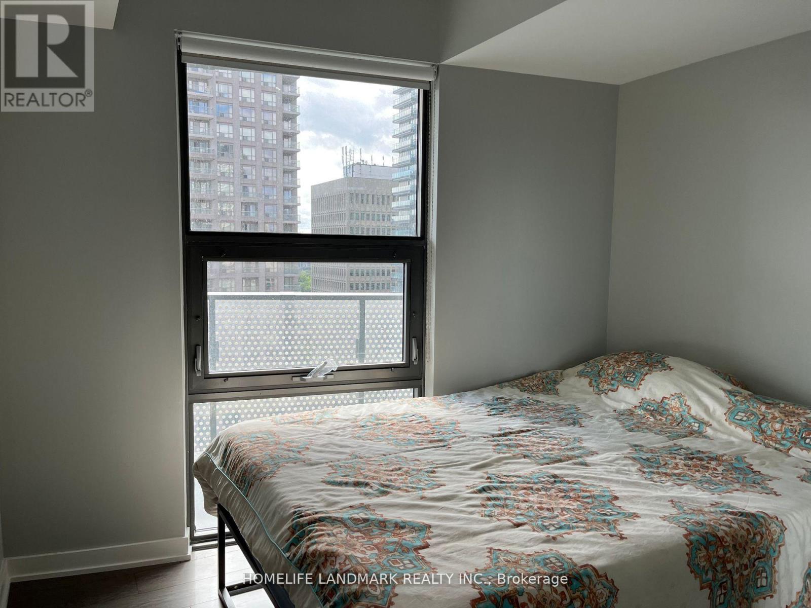 A bedroom with a large bed and a window overlooking a cityscape.