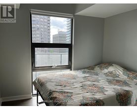 A bedroom with a large bed and a window overlooking a cityscape.