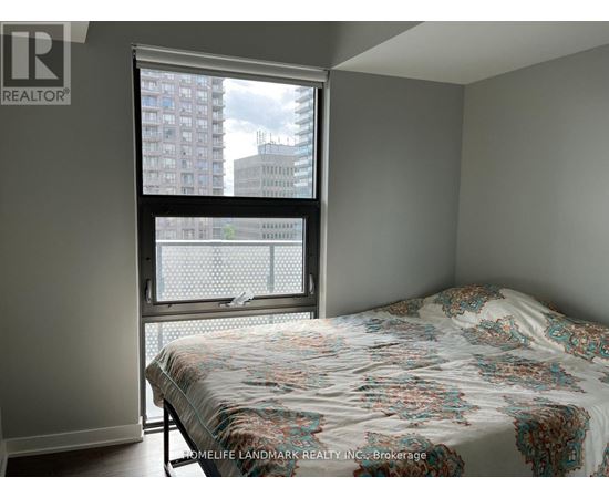 A bedroom with a large bed and a window overlooking a cityscape.