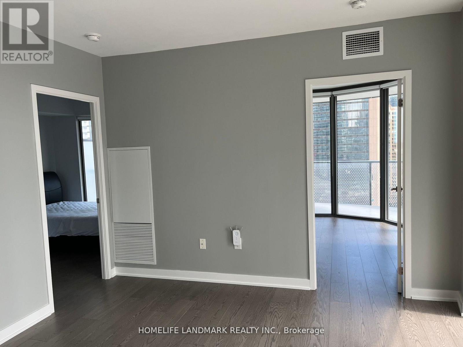 A bedroom with a bed, a closet, and a door leading to a balcony.
