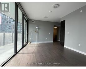 A spacious room with wooden flooring and a sliding glass door leading to a balcony.