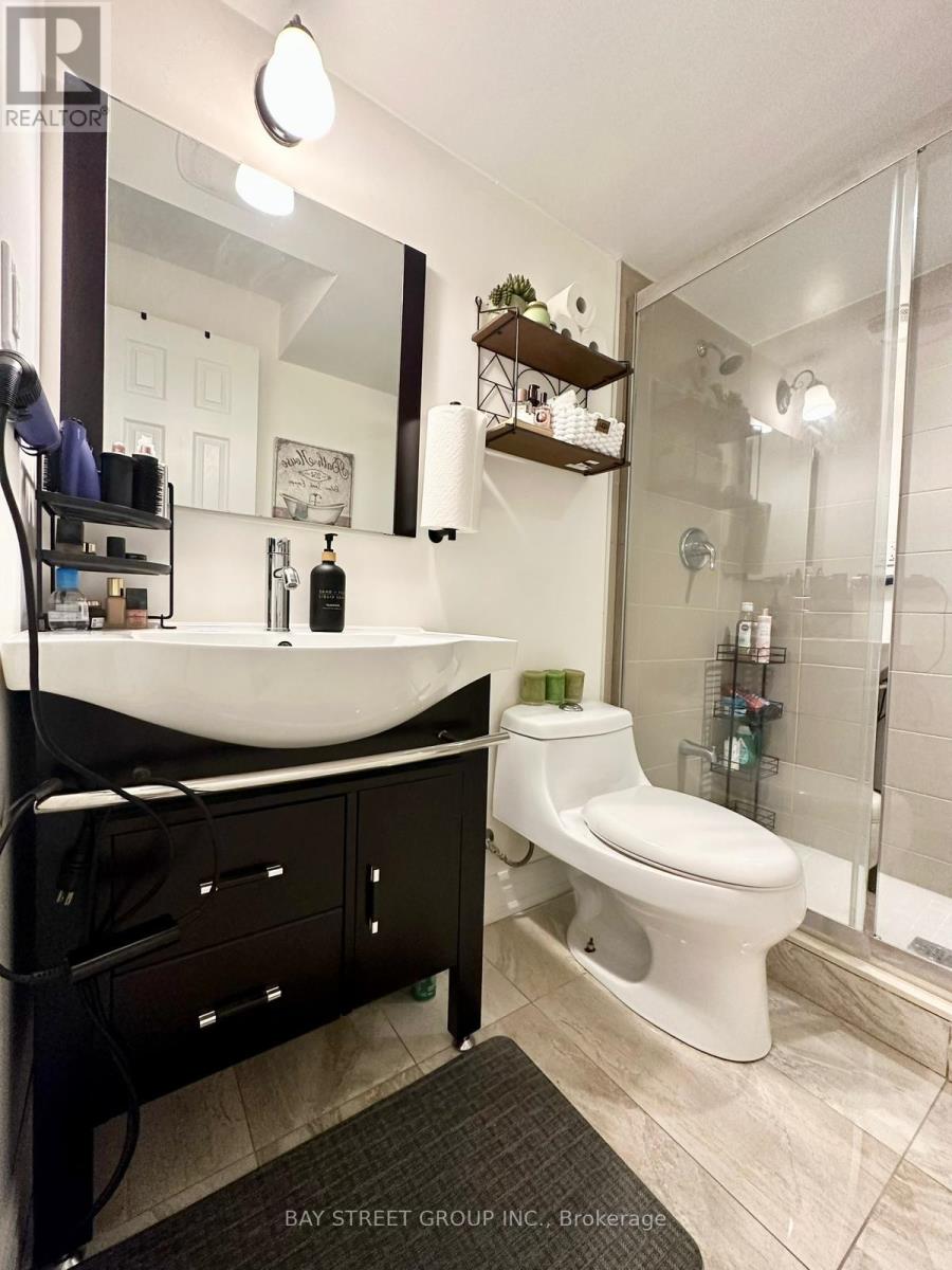 A white toilet is in a bathroom with a sink and mirror.