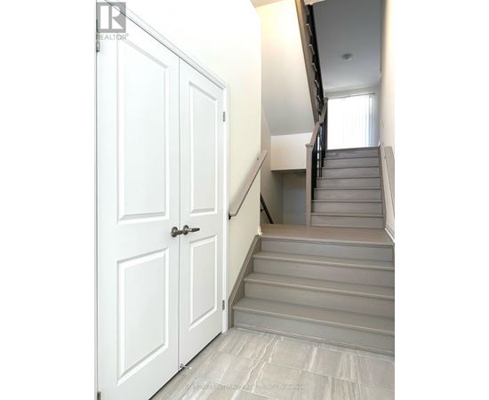 A white door is on the left and a staircase is on the right.