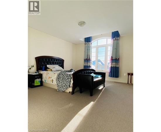 A bedroom with a large bed and a window with curtains.