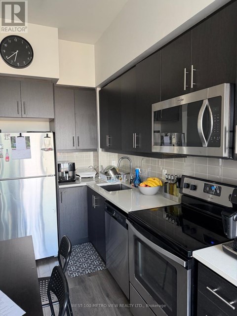 A kitchen with black cabinets and a stainless steel refrigerator.