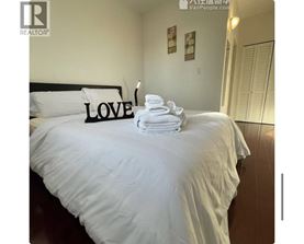 A bed with white sheets and a black headboard with the word LOVE on it.