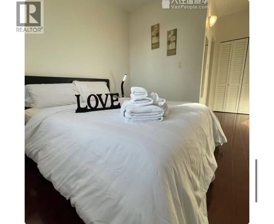 A bed with white sheets and a black headboard with the word LOVE on it.