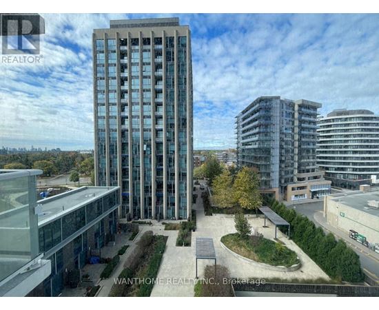A tall building with many windows is surrounded by other buildings.
