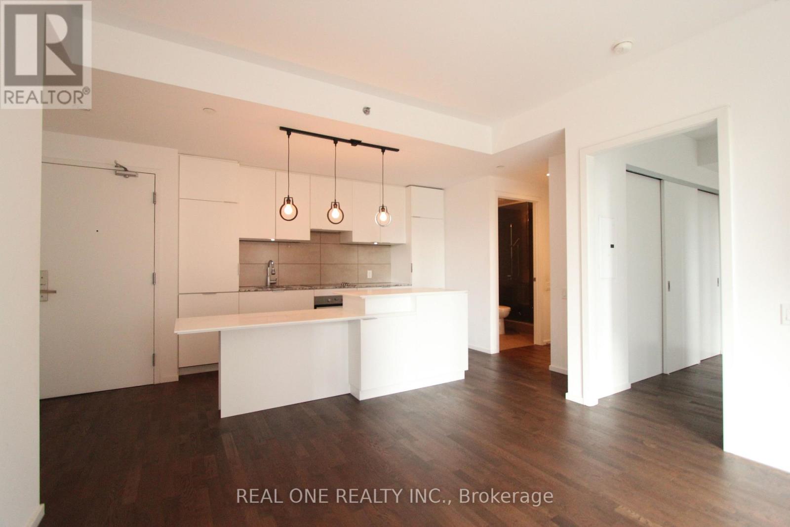 A real estate brokerage office with a white interior and wood flooring.