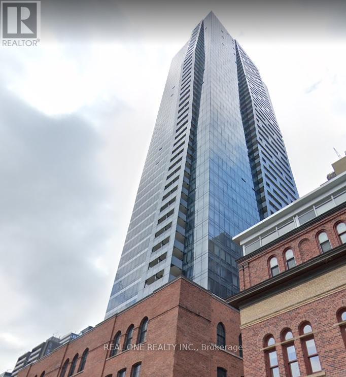 A tall skyscraper with a glass facade stands next to a red brick building.