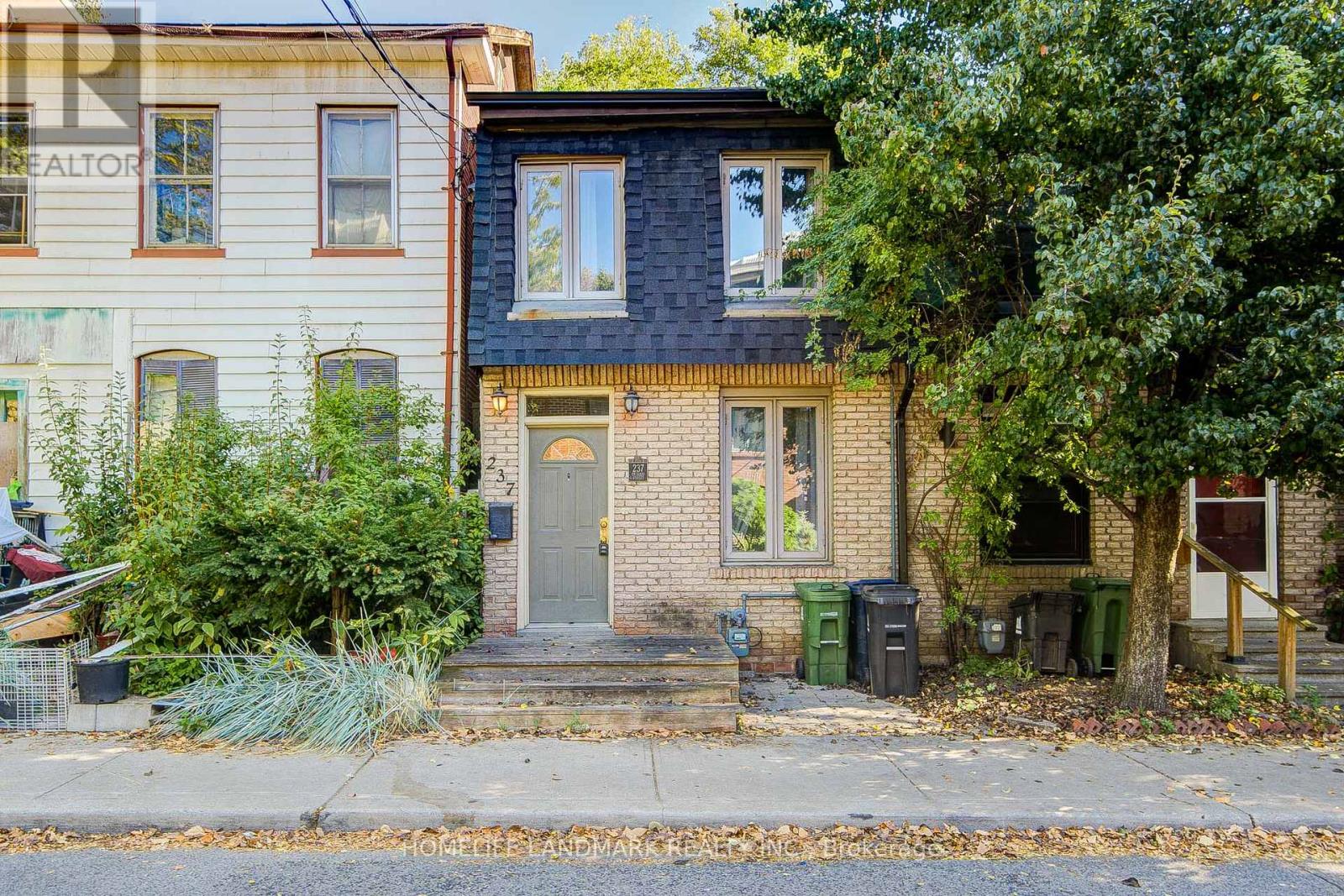 A house with a grey door and windows surrounded by greenery.