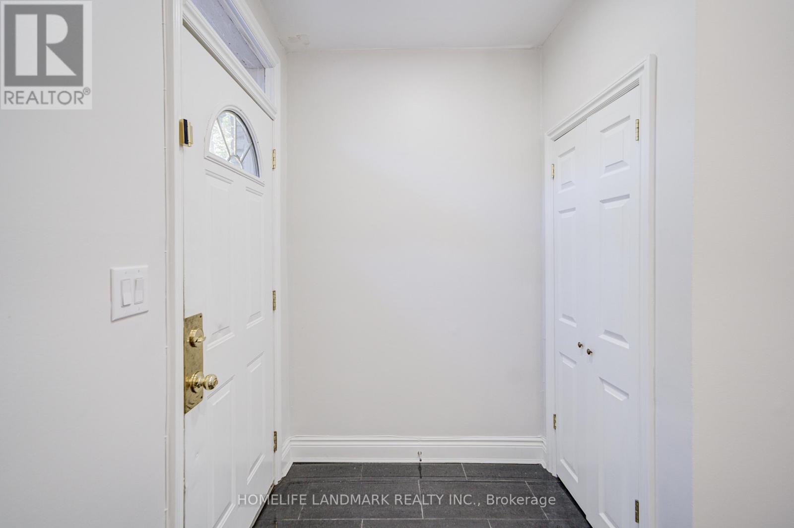 A white door with a gold handle is in a white room.
