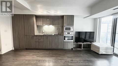 A spacious living room with a grey sofa and a television.