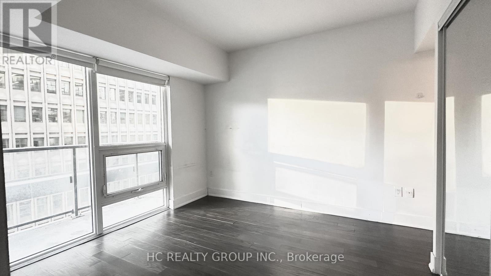 A room with a view of a building through the windows.