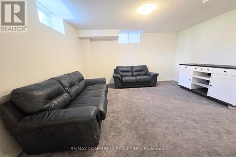 A living room with a black leather couch and a black leather chair.