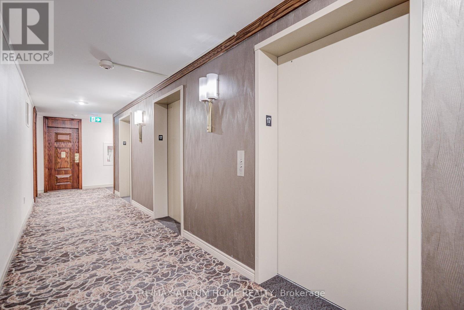 A hallway with a carpeted floor and doors on both sides.