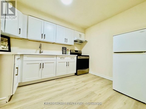 A kitchen with white cabinets and a fridge.