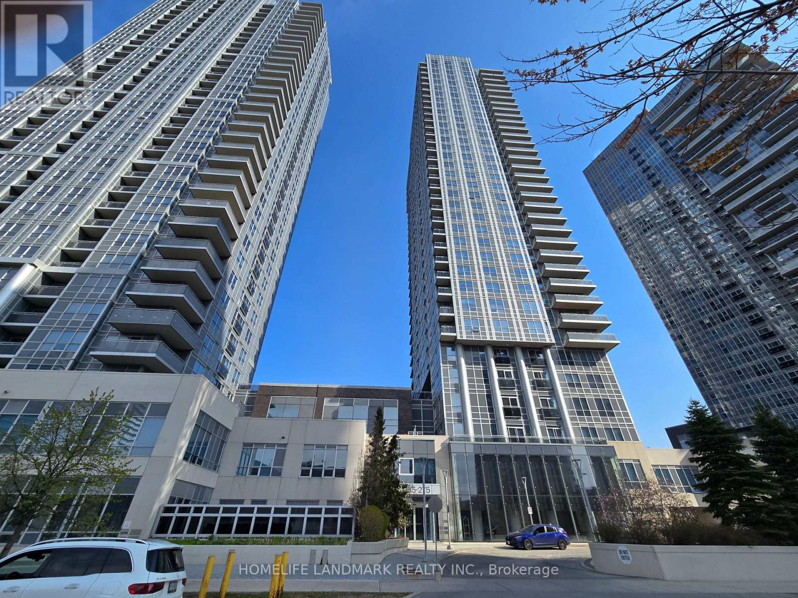 Two tall buildings stand next to each other with a Home Life Landmark Realty Inc. sign in the foreground.