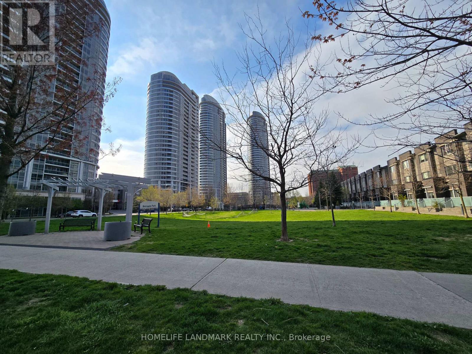 A park with a grassy area and a bench in front of a building.