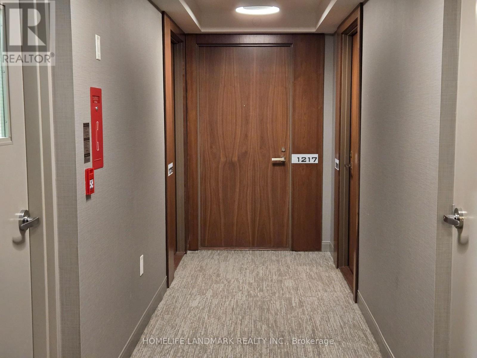 A hallway with a wooden door and a red fire extinguisher on the wall.