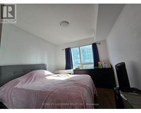 A bedroom with a bed, nightstand, and window.