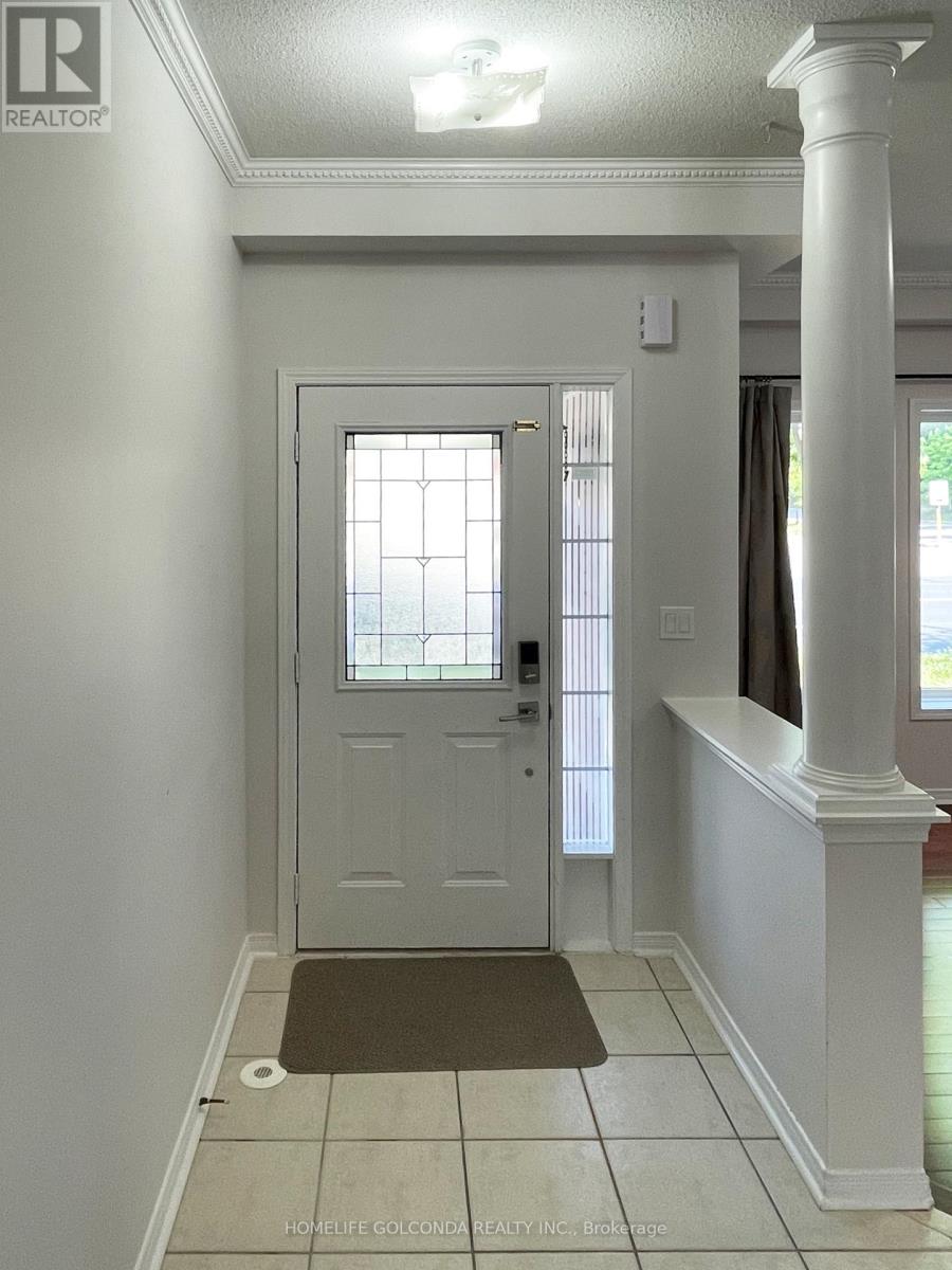 A white door with a glass window is in a hallway with a brown mat on the floor.