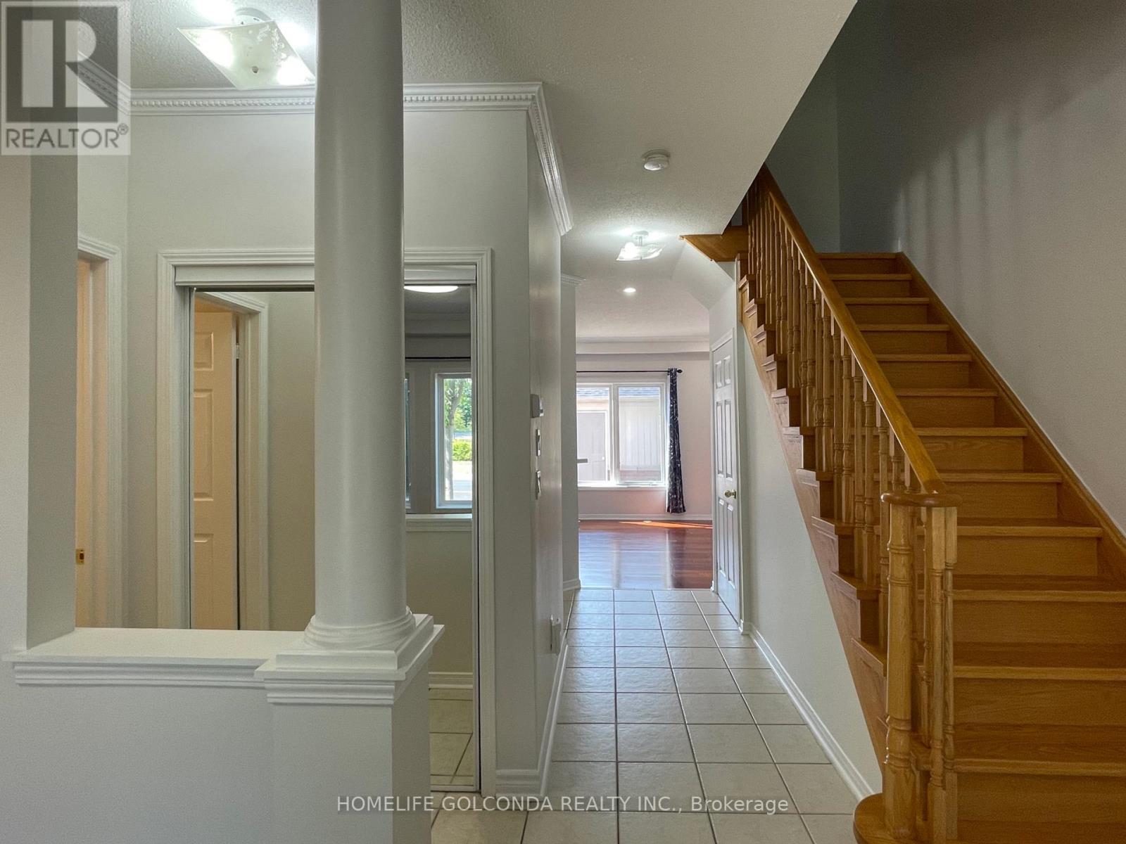 A hallway with a staircase and a doorway leading to another room.