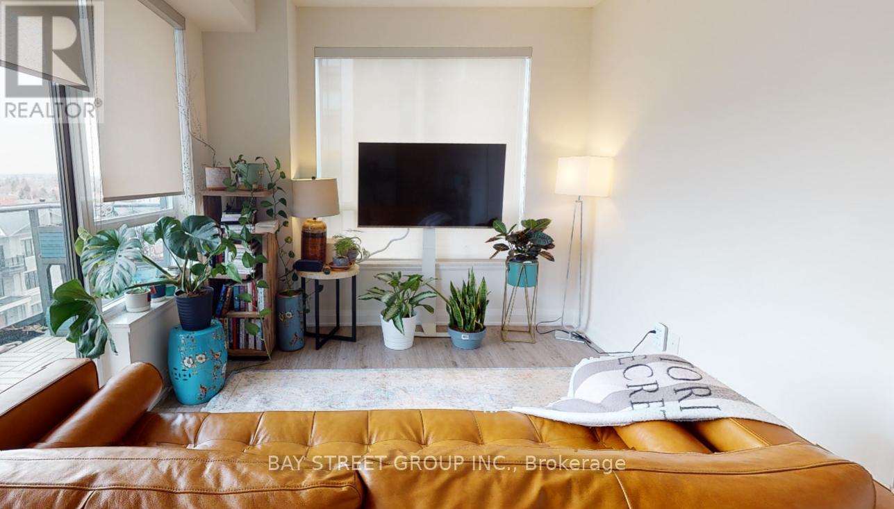 A living room with a brown leather couch and a flat screen TV mounted on the wall.
