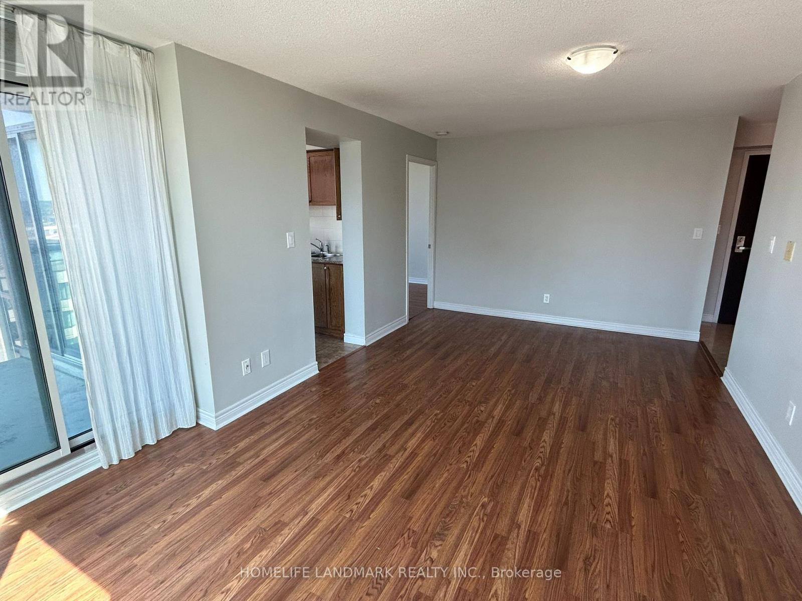 A spacious room with wooden flooring and white walls.