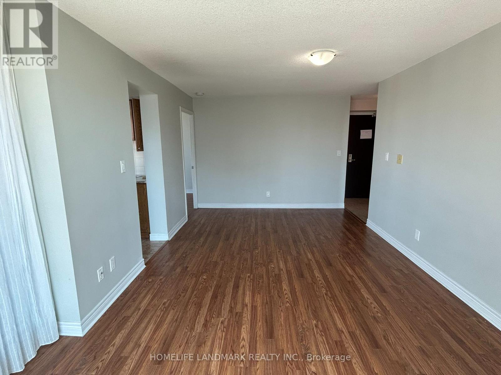 A long, empty hallway with wood flooring and white walls.