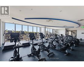A gym with a row of treadmills and elliptical machines.
