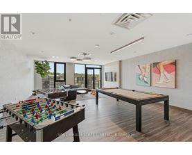 A foosball table is in the middle of a room with a pool table and a painting on the wall.