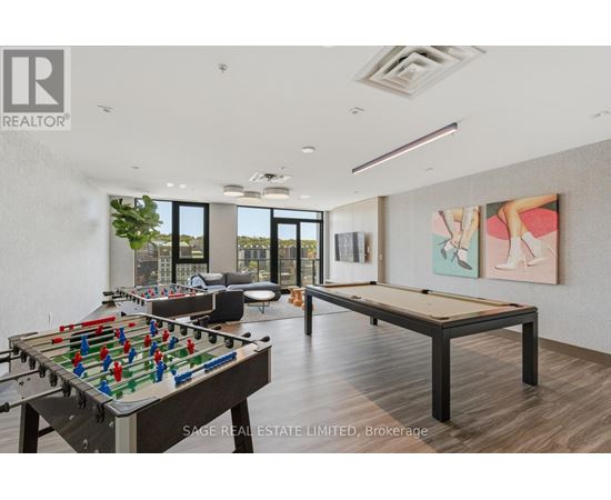 A foosball table is in the middle of a room with a pool table and a painting on the wall.