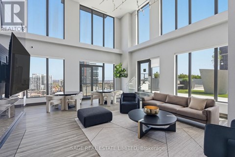 A living room with a black couch and a wooden floor.
