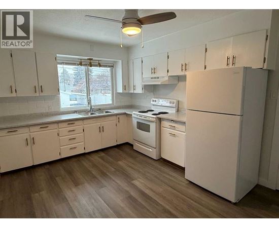 A kitchen with white cabinets and a refrigerator.