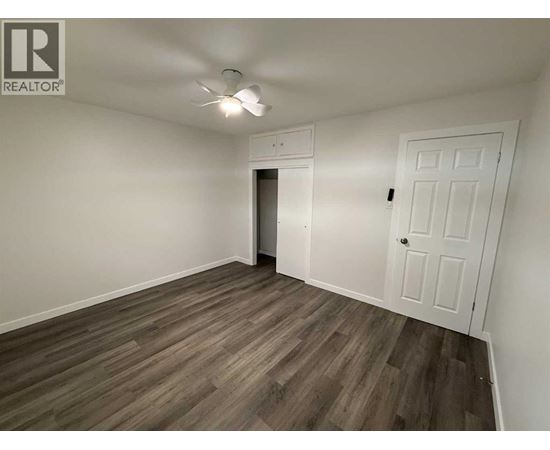 A room with a white door and a ceiling fan.