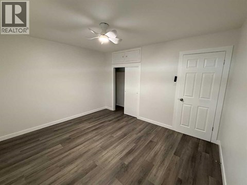A room with a white door and a ceiling fan.