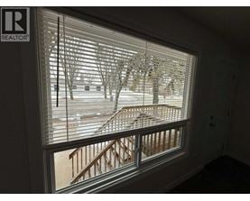 A window with blinds showing a snowy landscape outside.