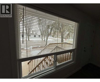 A window with blinds showing a snowy landscape outside.