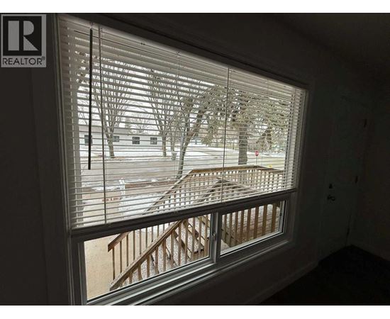 A window with blinds showing a snowy landscape outside.