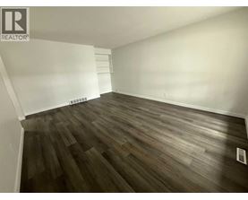 A room with wooden flooring and white walls.