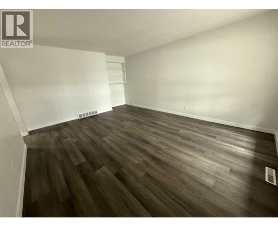A room with wooden flooring and white walls.