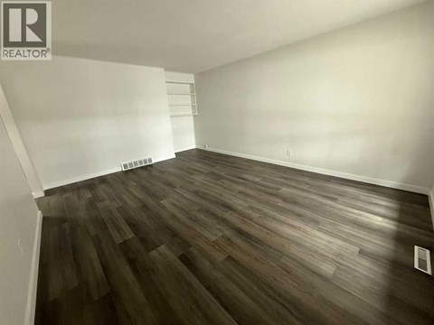 A room with wooden flooring and white walls.