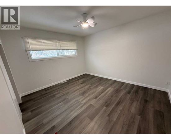 A room with wooden flooring and a window with blinds.